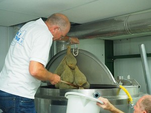 Sytze Hoogstins haalt de kruidenbuiltjes met gagel uit de kokend hete worttank. Loonbrouwer Gerrit Admiraal helpt hem daarbij, want de zakjess zijn na enkele minuten trekken loodzwaar geworden.